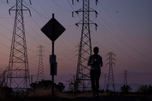 A woman jogs by power lines, as Californias grid operator urged the states 40 million people to ratchet down the use of electricity in homes and businesses as a wave of extreme heat settled over much of the state.png